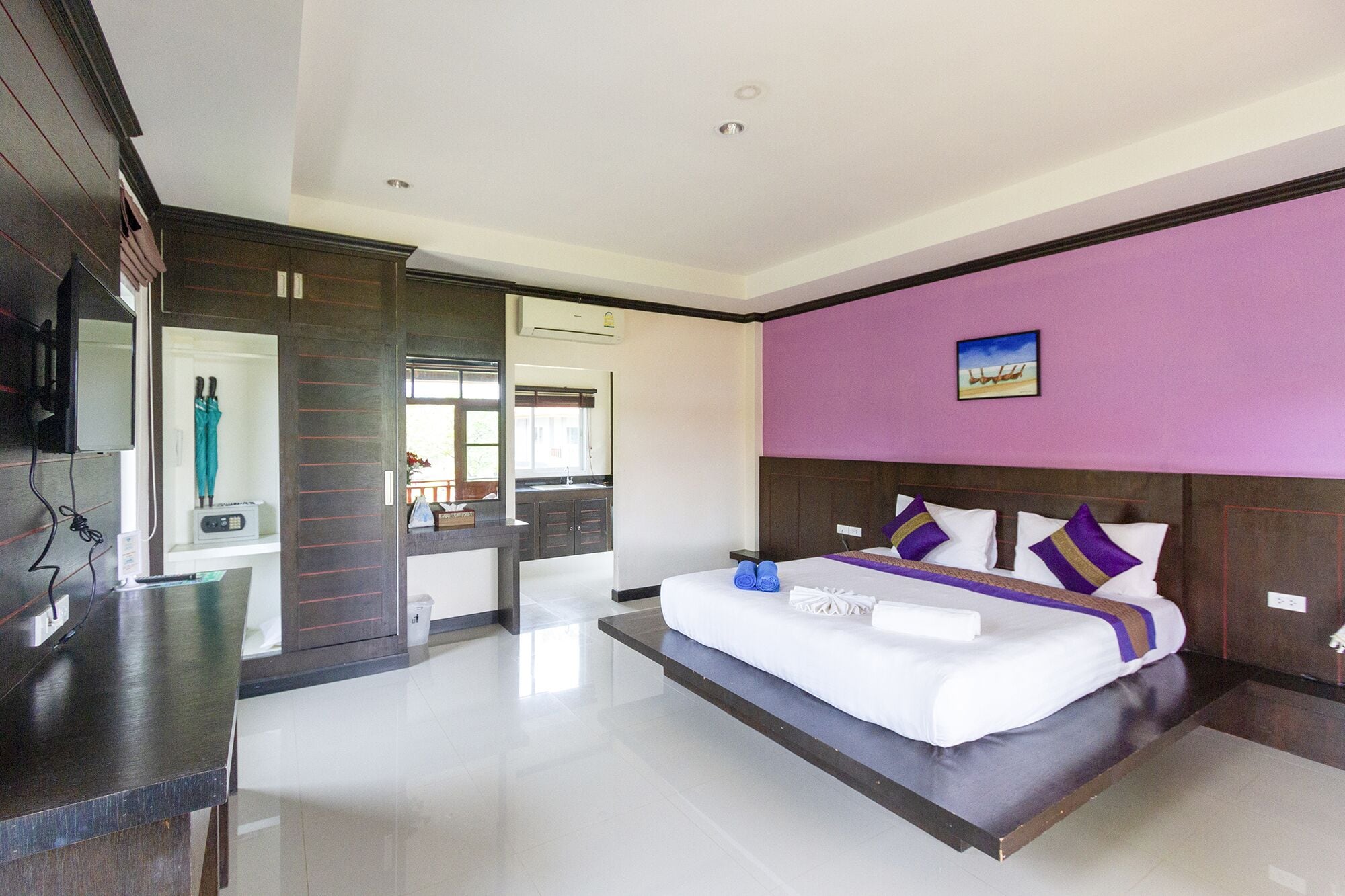 A modern hotel room with a large bed, a vanity with a mirror, and a view of the room's interior.