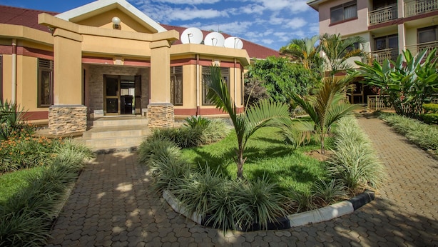 A building with a central entrance, satellite dishes on the roof, and a paved pathway leading to the entrance.
