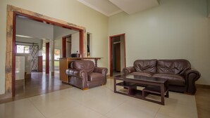 A spacious living room with two leather sofas, a wooden coffee table, and a large mirror.