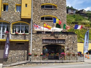 Ein Hotel mit Steinfassade, mehreren Flaggen und Blumenkästen.