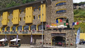 A hotel with a stone facade, multiple balconies, and outdoor seating. - Hotel Les Terres (Canillo)