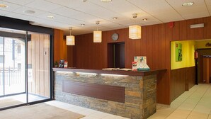 A reception area with a stone counter, wooden panel walls, and a clock. - Hotel Les Terres (Canillo)