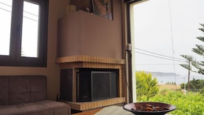 Una sala de estar con chimenea, un sofá y vistas a zonas verdes y montañas.