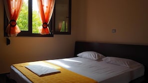 Una cama individual con cabecera de madera, almohada blanca y manta amarilla.