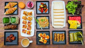 A variety of dishes including croissants, grilled meat, fried rice, and fruit.