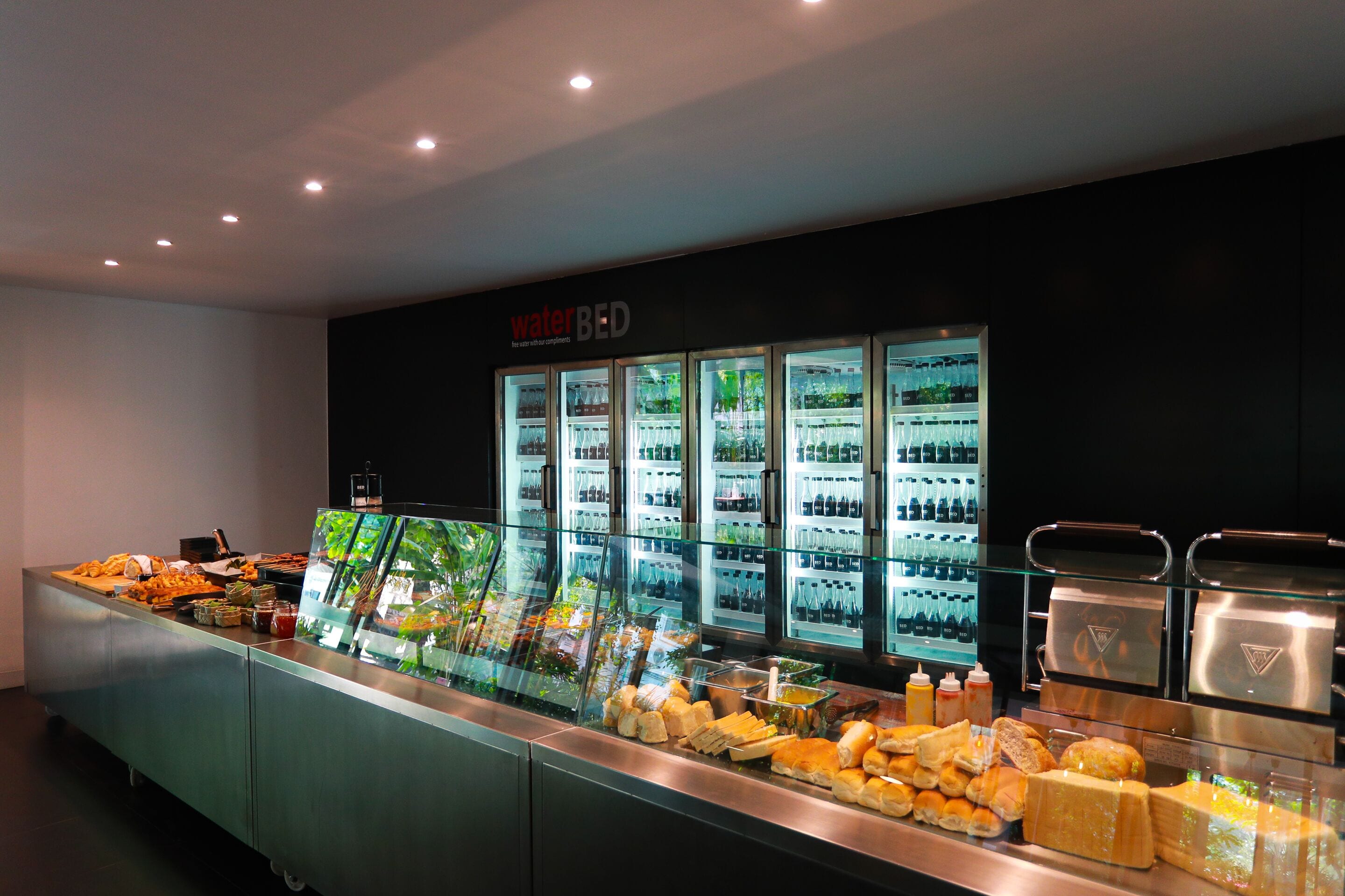 A buffet area with a waterbed sign, various food items, and a refrigerated display case.
