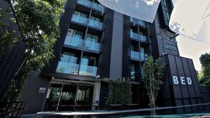 Un edificio moderno con un letrero que dice "BED" en la fachada, con varios balcones y una entrada de vidrio.