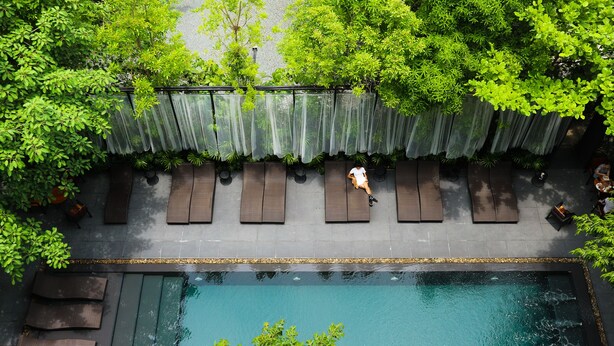 Vista aérea de un área de piscina en la azotea con una fila de sillones reclinables y una piscina.