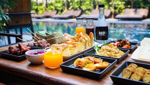 Un bufé con diversos platos, bebidas y ambiente junto a la piscina.