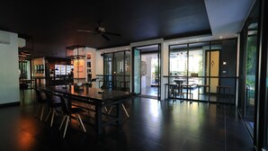 Un moderno vestíbulo de hotel con un amplio comedor, una recepción y grandes ventanales que ofrecen vistas al exterior.