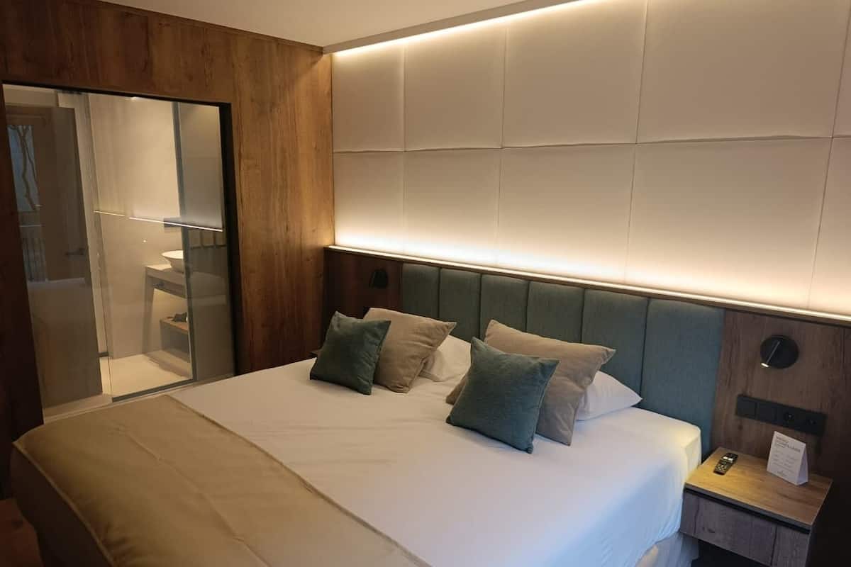 Una habitación de hotel con cama, mesita de noche y espejo.