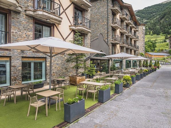 A stone building with outdoor seating and umbrellas.
