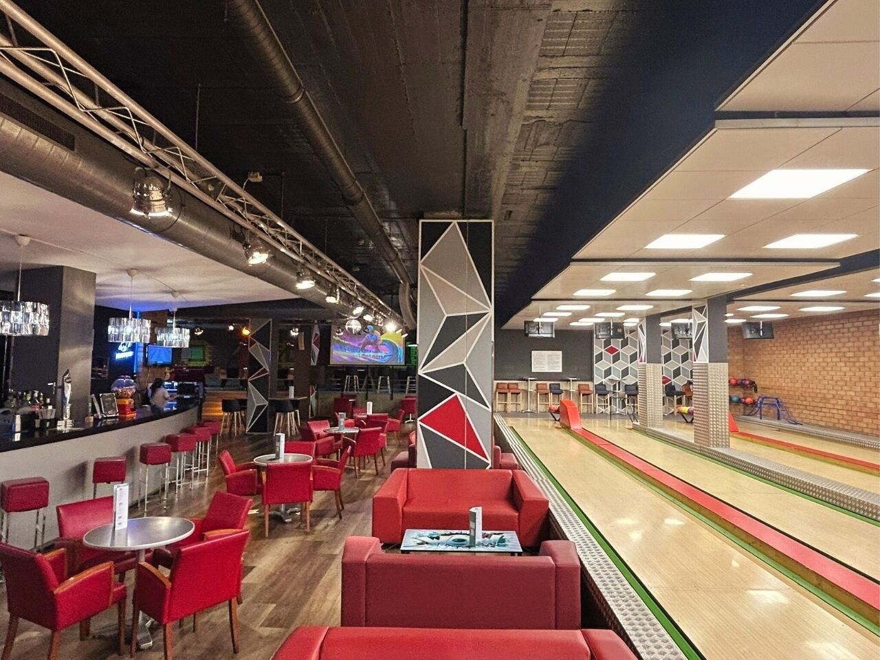A bowling alley with red seating and a bar area.