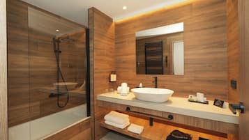 Un baño moderno con ducha de vidrio, lavamanos blanco y paneles de madera.