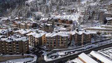 A snow-covered resort with multiple buildings, roads, and a mountain backdrop.