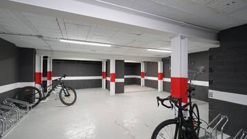 A parking garage with bicycles, concrete pillars, and a white and red color scheme.