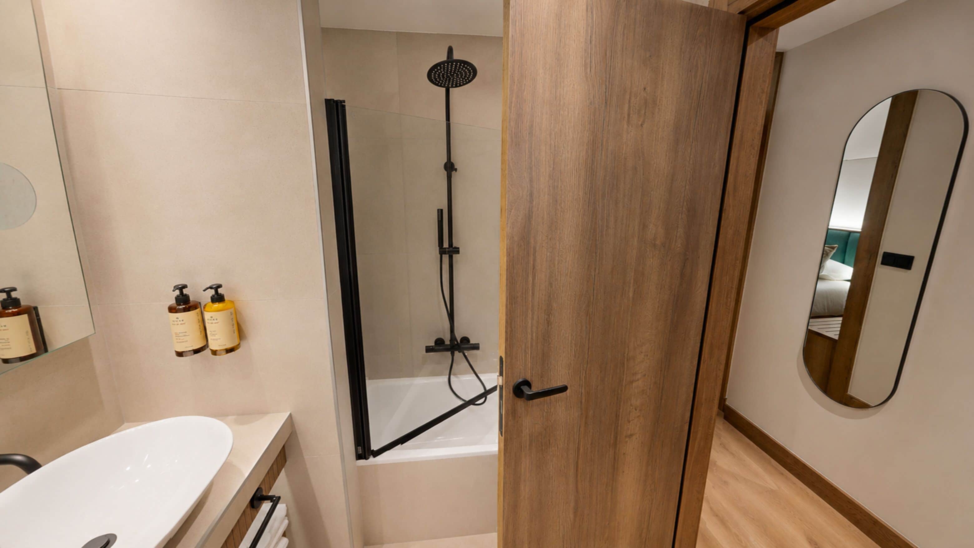 Ein modernes Badezimmer mit Badewanne, Dusche und einer Holztür.