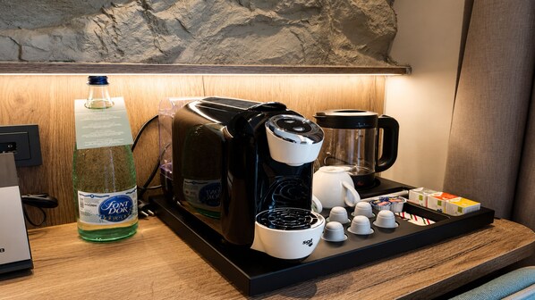A coffee station with a coffee maker, a water bottle, and sugar packets on a wooden table. - Hotel Spa Princesa Parc Excellence (Arinsal)