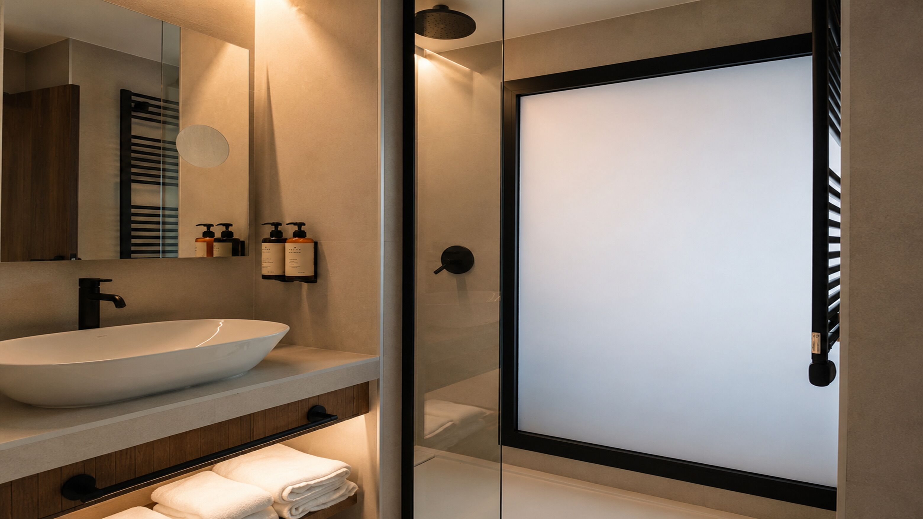 Une salle de bain moderne avec un grand lavabo sur pied, un miroir et une cabine de douche en verre.