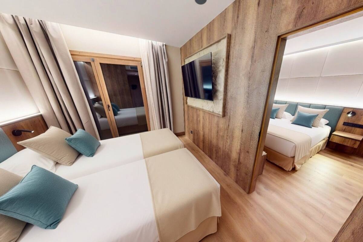 Una habitación de hotel con dos camas, un panel decorativo de madera, un espejo grande y un televisor.