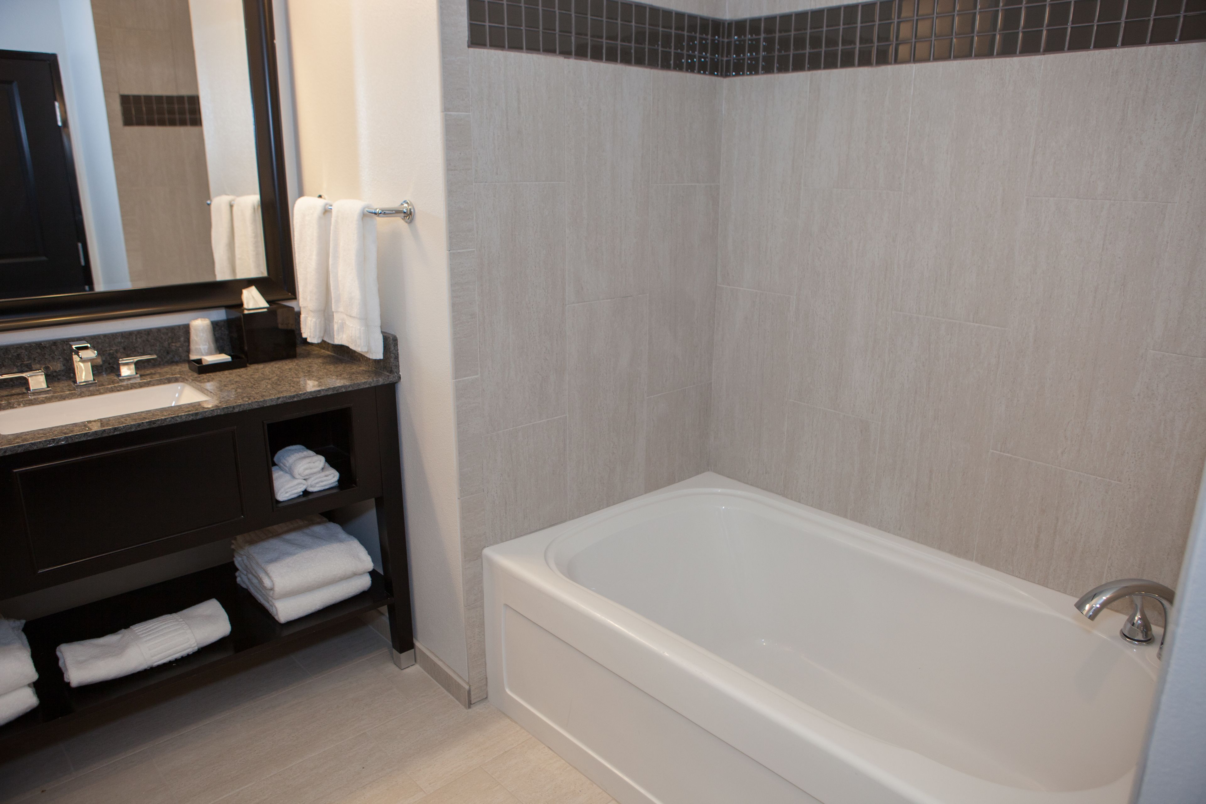 Een moderne badkamer met een groot bad, een wastafelmeubel en een spiegel.