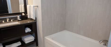A modern bathroom with a large bathtub, a vanity with a sink, and a mirror.