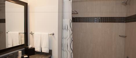 A modern bathroom with a large mirror, a sink, a shower with a glass door, and a bathtub.