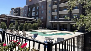 A hotel with a pool area, outdoor seating, and a clear sky.