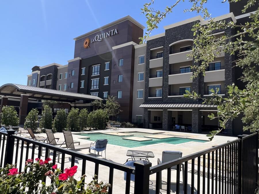 A hotel with a pool area, outdoor seating, and a clear sky.