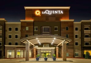 Un hotel con un llamativo letrero de "La Quinta", un acceso cubierto y varias ventanas.