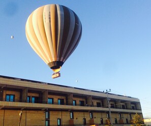 Un globo aerostático con una canasta, volando sobre un edificio de varios pisos con balcones.