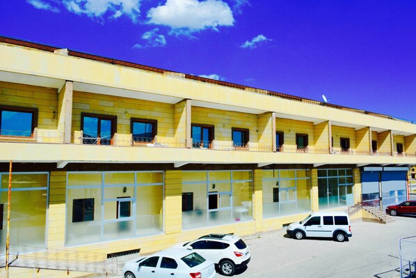 Un edificio de varios pisos con amplios ventanales y balcones. Varias coches están estacionados al frente.