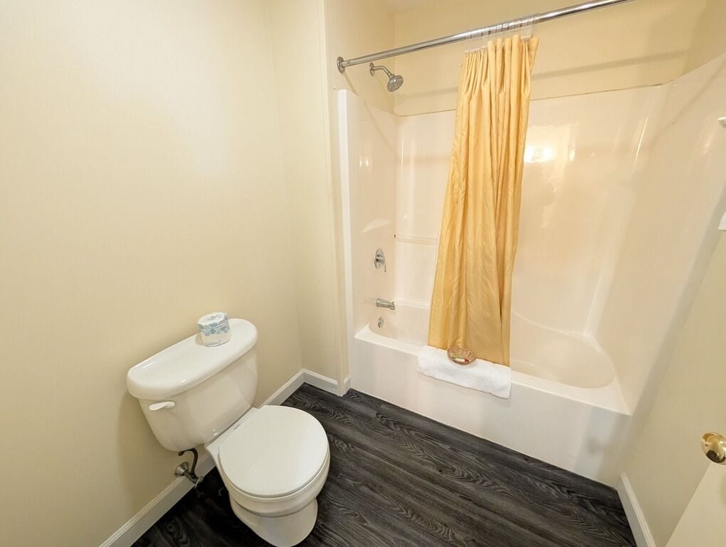 Et badeværelse med toilet, badekar og bruseforhæng.