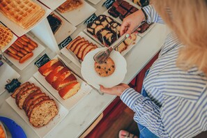 A person selecting a cookie from a display of various baked goods.