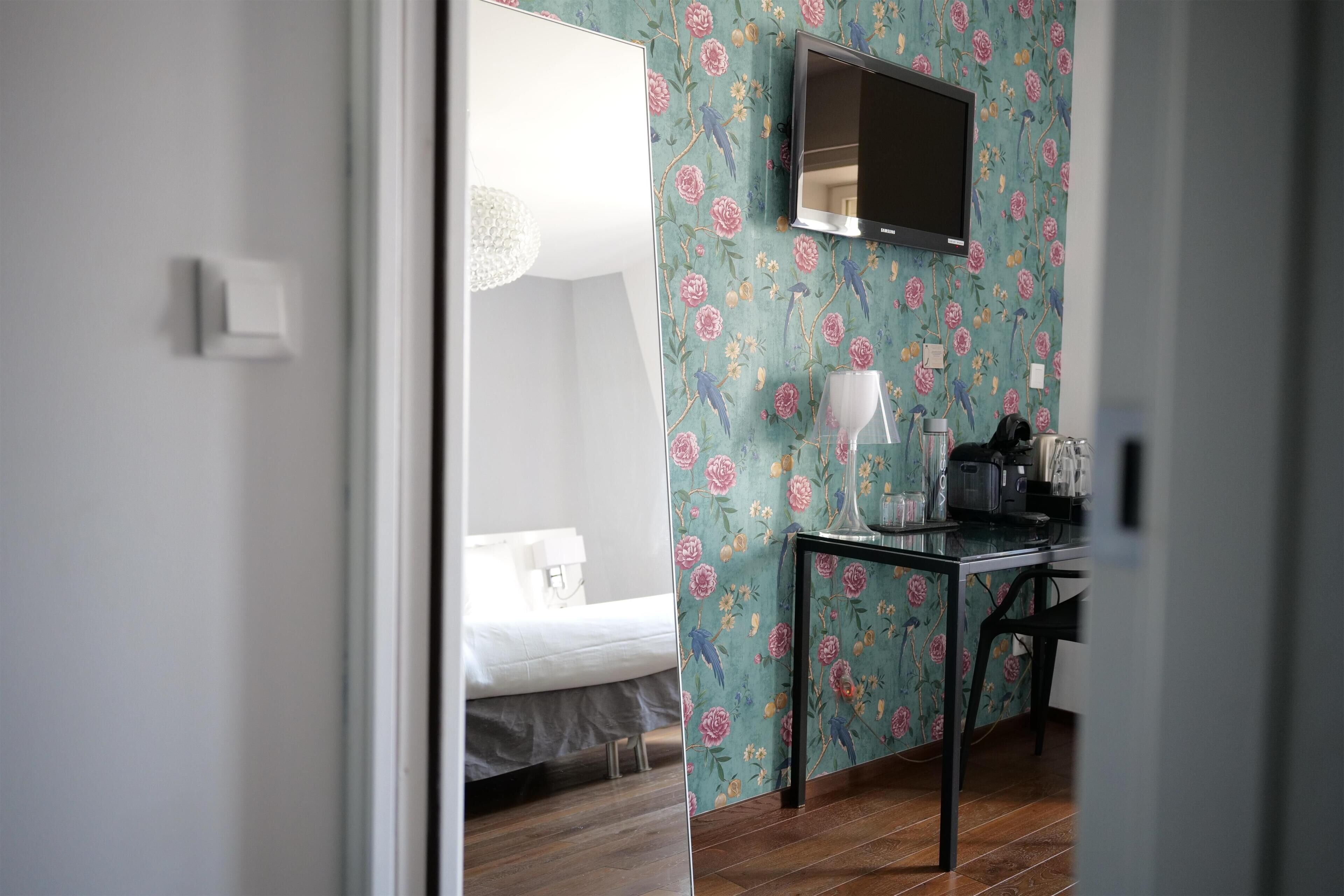 Una habitación con una cama, un escritorio con lámpara y un televisor montado en la pared.