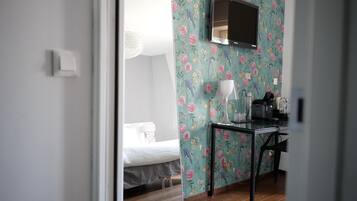 Una habitación con una cama, un escritorio con lámpara y un televisor montado en la pared.