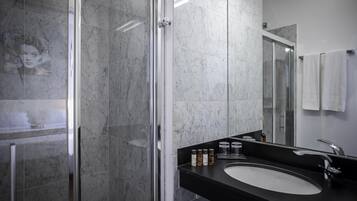 Een moderne badkamer met een douchecabine van glas, een zwart aanrecht en een witte wastafel.