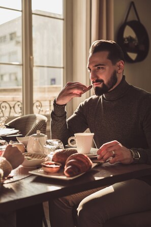 A person sitting at a table with a teapot, cups, and pastries. - Le Manoir Hotel, BW Signature Collection (La Rochelle)