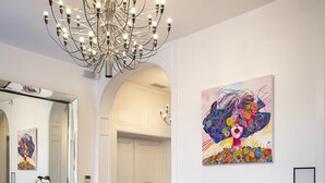A hotel lobby with a modern chandelier, a colorful armchair, a large abstract painting, and a reception desk. - Le Manoir Hotel, BW Signature Collection (La Rochelle)