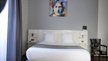 Ein Hotelzimmer mit einem großen Bett, zwei Nachttischen, einem Sessel und einem Gemälde an der Wand.
