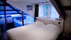 A bedroom with a bed, a window, and a bathroom visible through an open door. - Hotel Restaurant het Rechthuis (Muiderberg)