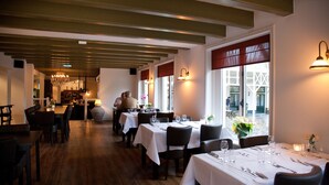 A restaurant with wooden floors, white tablecloths, and candlelit tables. - Hotel Restaurant het Rechthuis (Muiderberg)