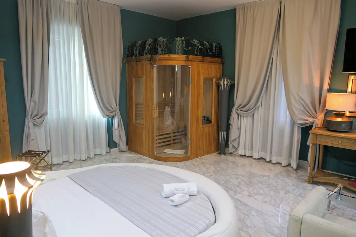 Quarto de hotel com cama, armário de madeira, chuveiro e televisão.