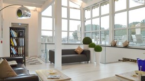 Un salón amplio con un gran ventanal, un sofá, una mesa de centro y una estantería.