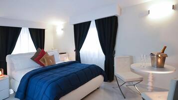 Ein modernes Hotelzimmer mit einem Bett, Nachttischen, einem kleinen Tisch mit einem Getränk und einem Sessel.