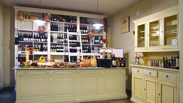 Una zona de bar con estantes llenos de botellas y diversos productos alimenticios sobre el mostrador.