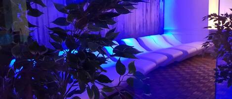 Una habitación con un sofá blanco, piso de madera y una pared iluminada en azul.