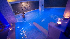 Una piscina interior con un cartel que dice "Villa Minerva", rodeada de muros de piedra e iluminación azul.