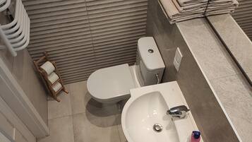 A bathroom with a toilet, sink, and towel stack.