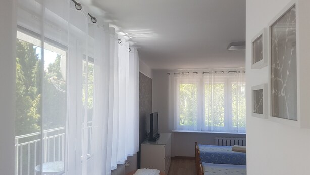A room with a bed, a TV, and a window with curtains.